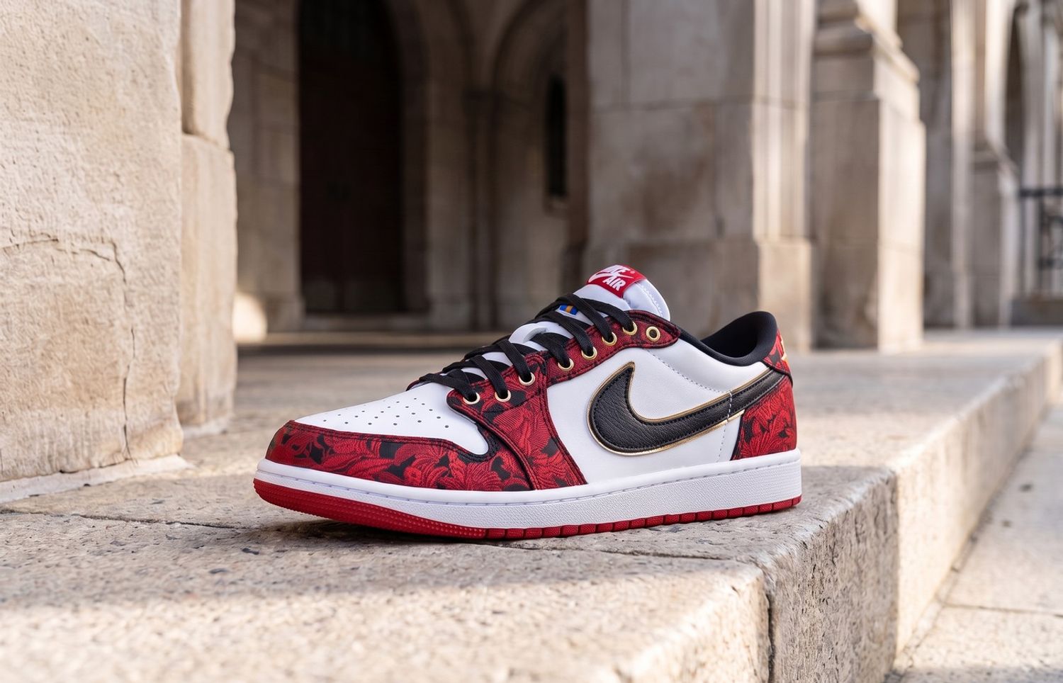 Air Jordan 1 Low OG Garden met rood bloemenborduurwerk en gouden details op een lichte stenen trap