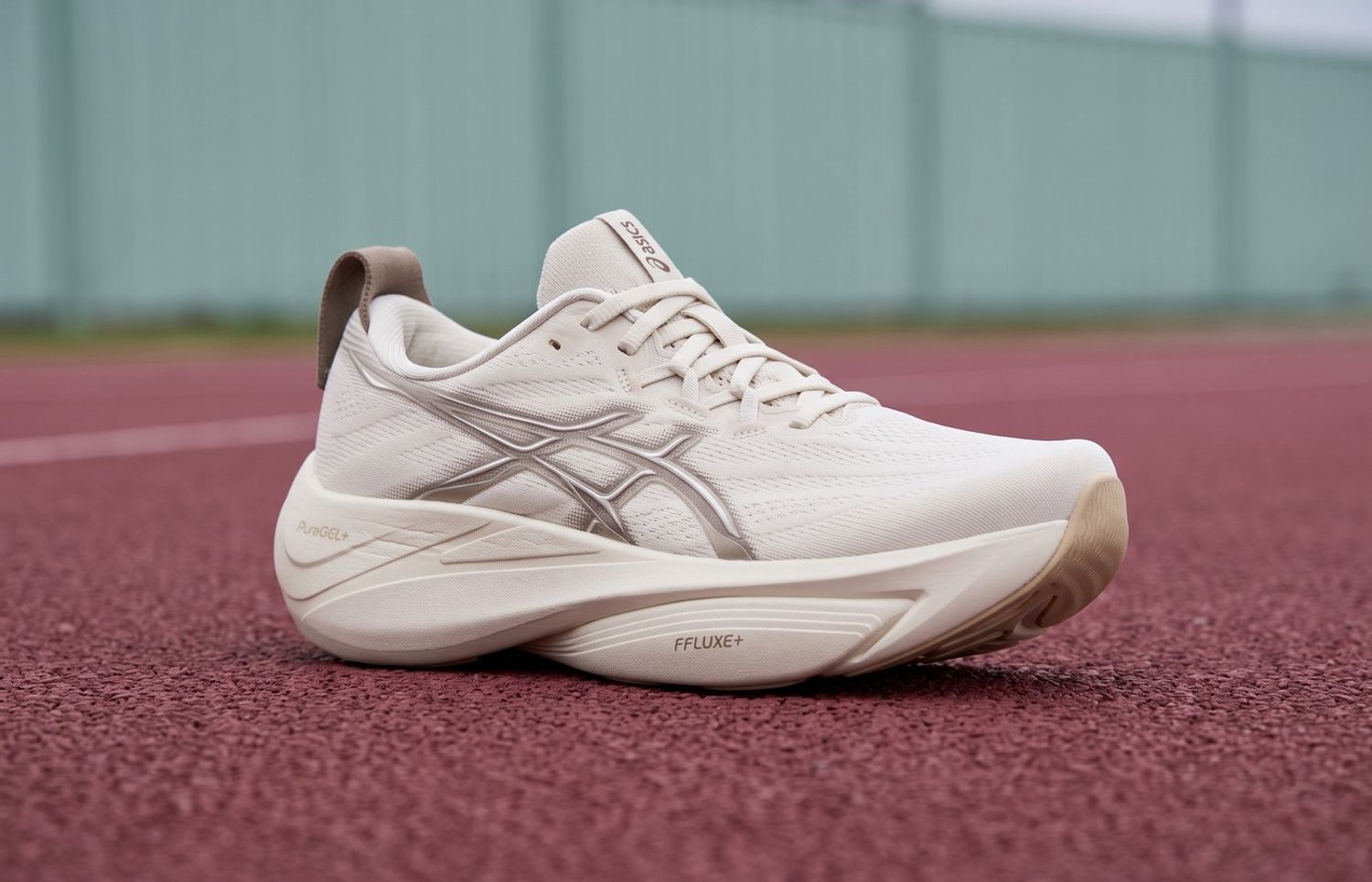 ASICS GEL-SLOWCUSH Soft Oat/Simply Taupe met crèmekleurige mesh en gebogen zool op een bordeauxrode atletiekbaan