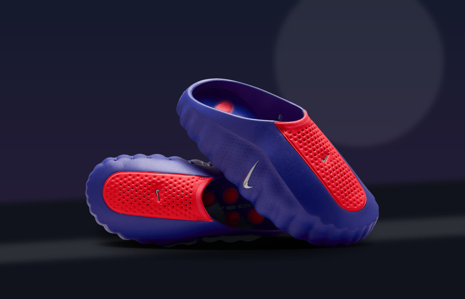Nike Mind 001 AMP Indigo Burst en Hyper Punch op een donkere trainingvloer