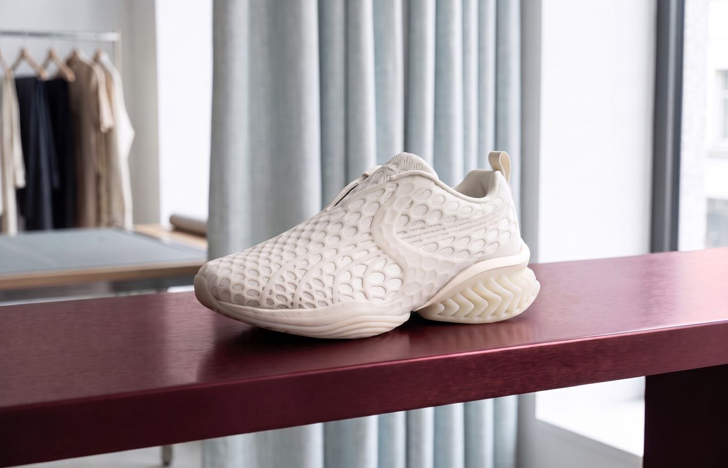 Puma x J.L-A.L CELL Geo Warm White met fijne TPU-kooi en open hielfins op een bordeauxrode plank in een atelier