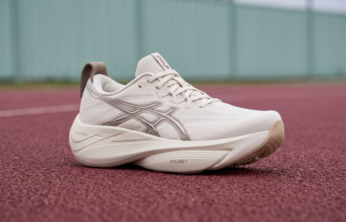 ASICS GEL-SLOWCUSH Soft Oat/Simply Taupe met crèmekleurige mesh en gebogen zool op een bordeauxrode atletiekbaan