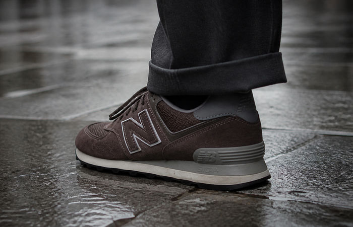 Bruine suède New Balance 574 op natte straatstenen