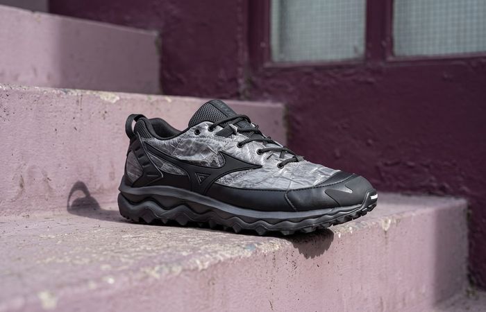 Han Kjøbenhavn x Mizuno Wave Mujin TL met gekreukte grijze upper, zwarte Runbird en golvende zool op een mauve betonnen trap