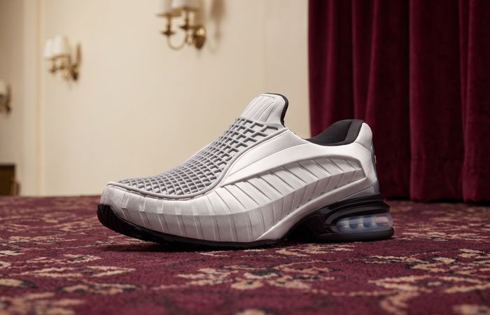Nike Air Max Dolce Metallic Silver met veterloze kooi-upper en zichtbare Air op bordeaux tapijt in een bioscoopfoyer
