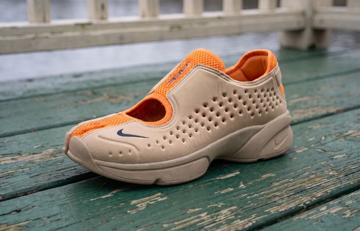 Nike Rift 2 Vivid Orange/Yukon Tan met oranje mesh, geperforeerde bruine upper en gespleten neus op een groene houten roeisteiger