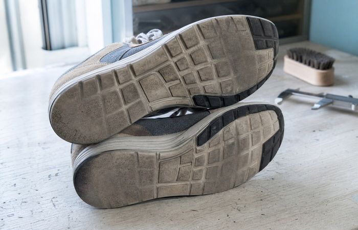 Twee sneakerzolen met verschillende slijtagepatronen op een werkbank